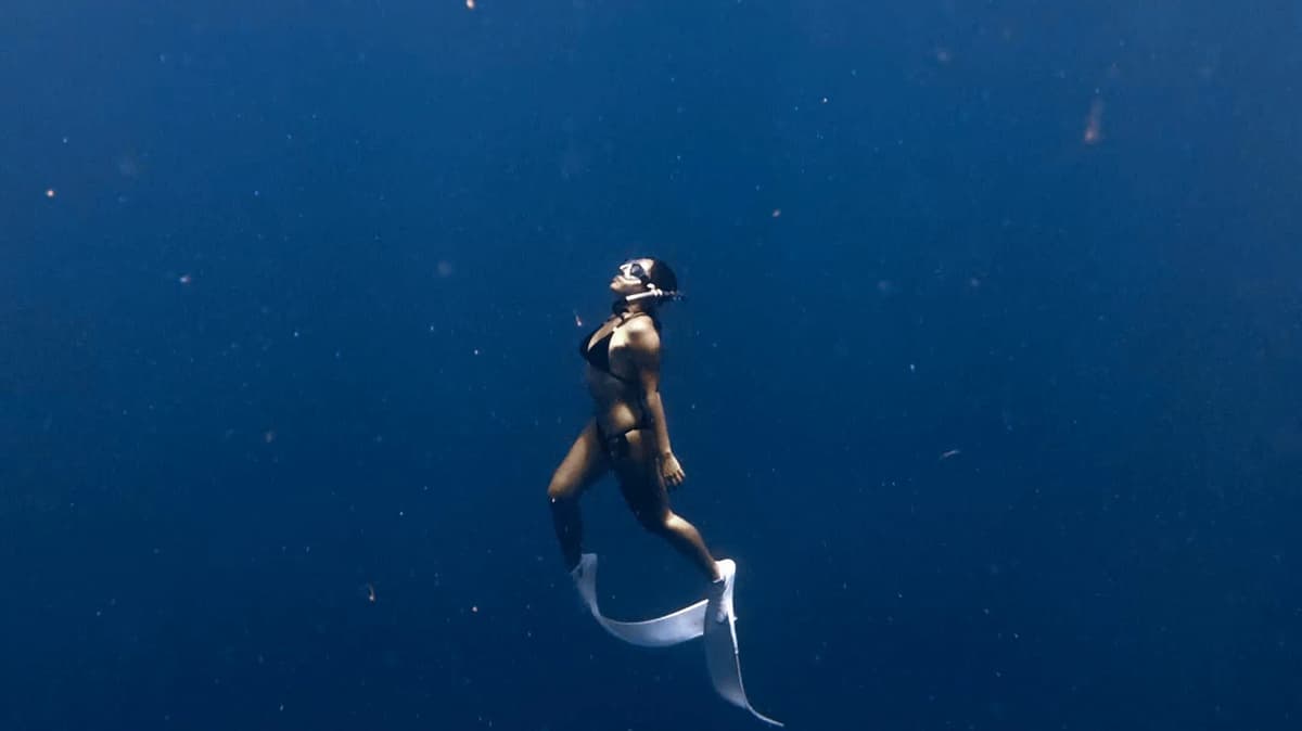 Freediver gliding mid-water in deep blue water