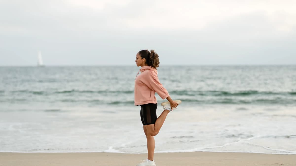 Woman stretching on a beach overlooking the sea
