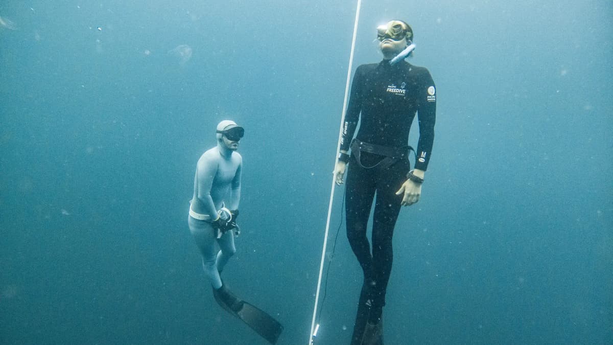 A freediving instructor and student on a descent line underwater