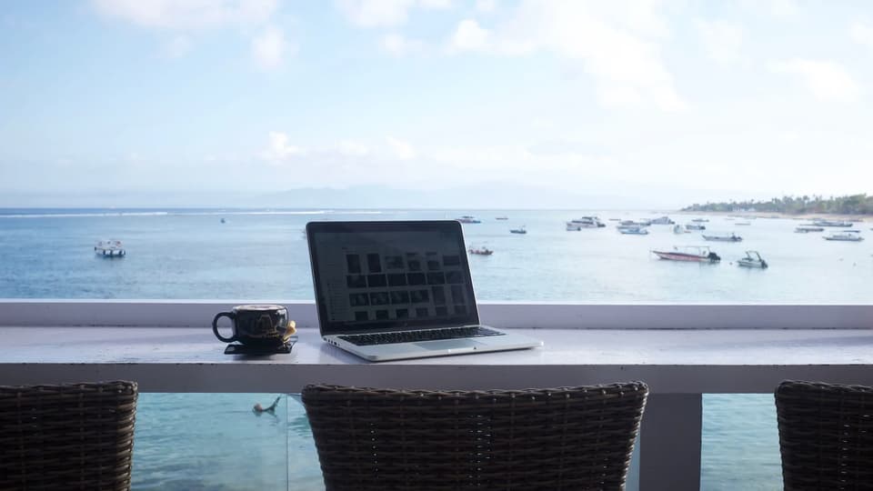 Laptop and coffee on a table overlooking the sea