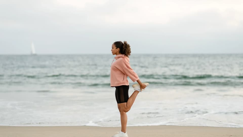 Woman stretching on a beach overlooking the sea